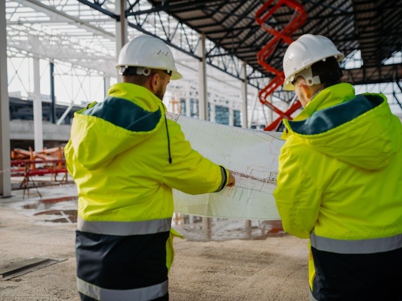 Construction manager coordinating project schedules, contractors, and building plans during a commercial construction project