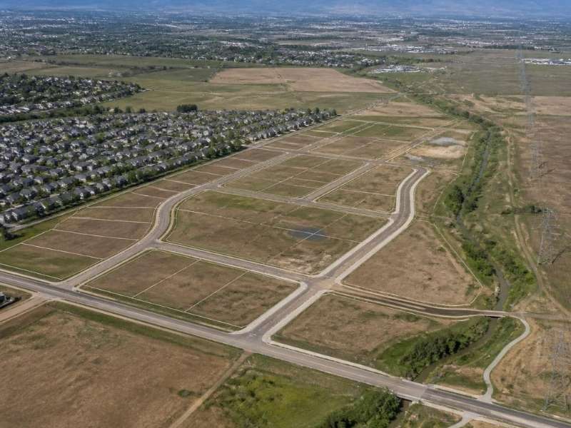 Aerial view of a large land development site with new roads, residential areas and open parcels planned for future construction.
